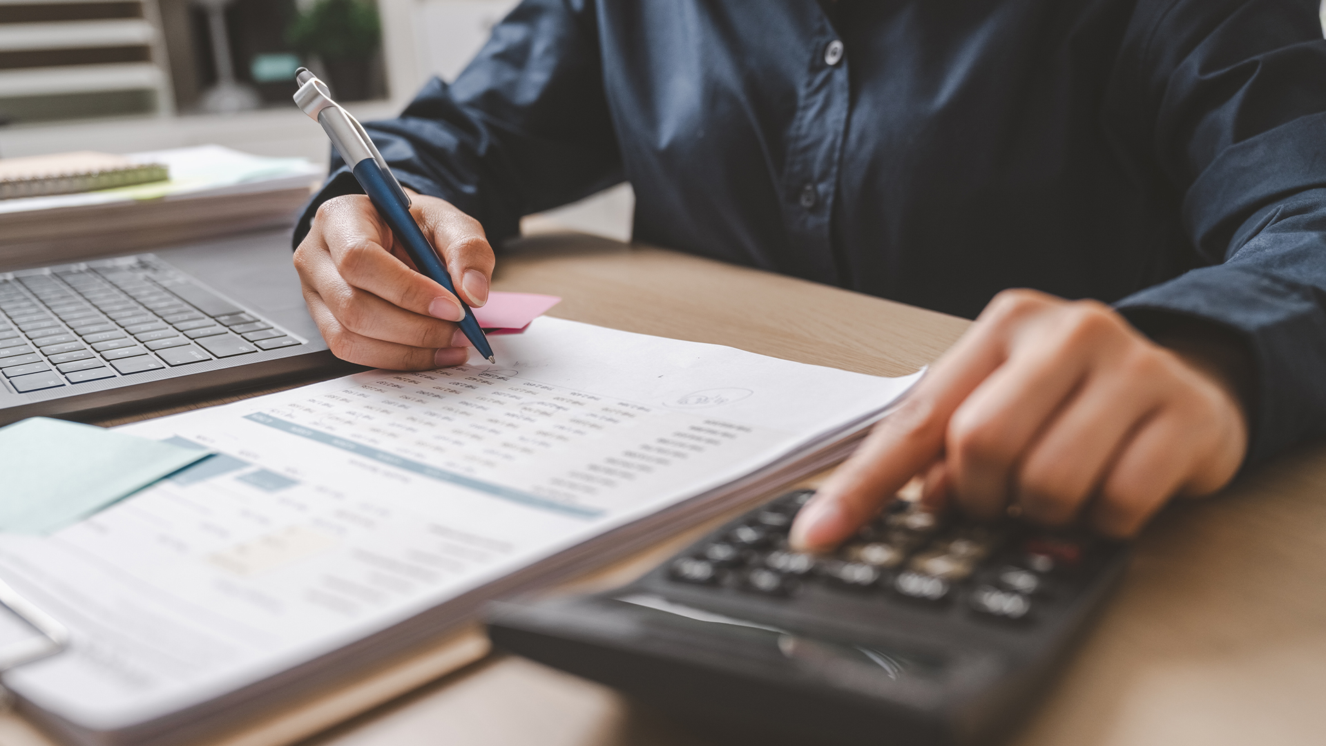 Image réporésantant une personne en train de travailler et de faire des calculs à l'aide d'une calculatrice.